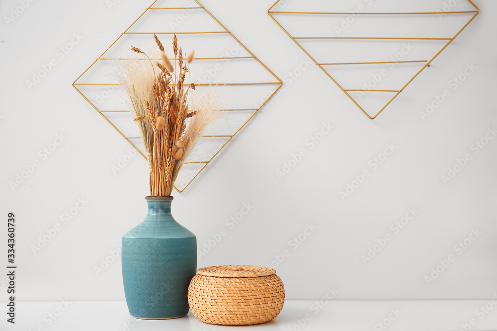 Vase with basket on table near white wall in room