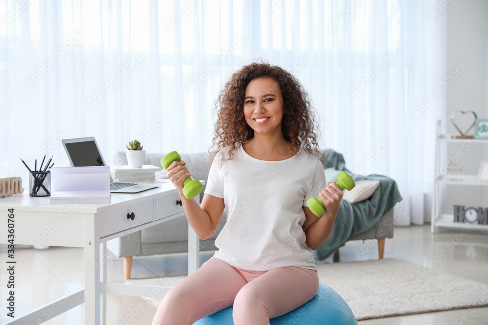 Young woman doing exercises with fitness ball at home