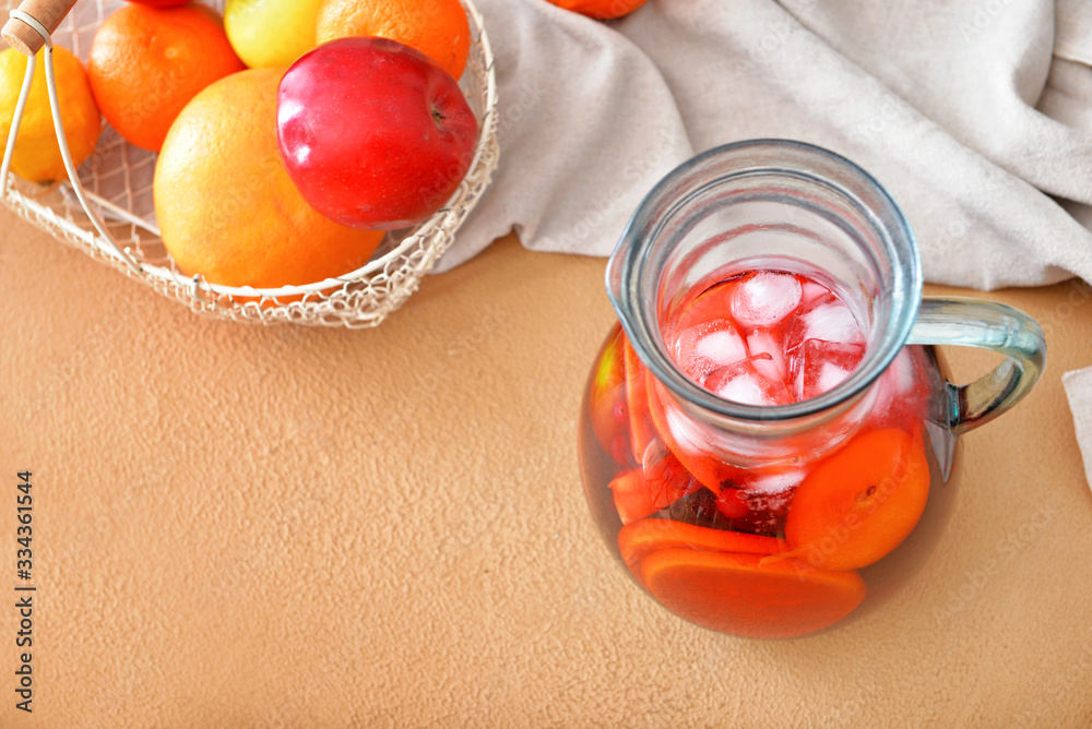 Jug of tasty cold tea on color background