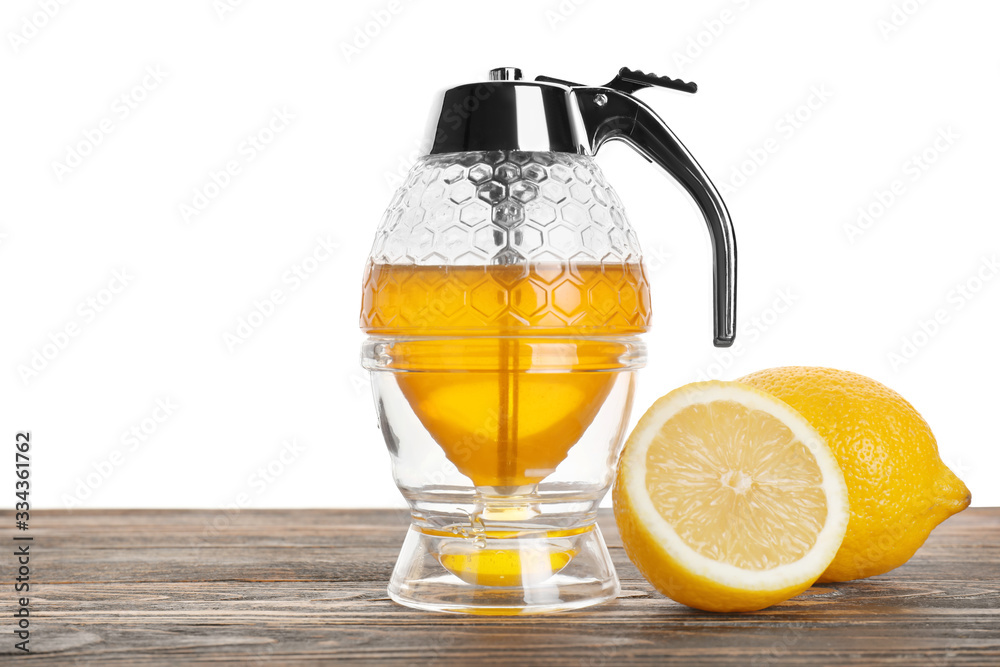 Honey-pot and lemon on table against white background