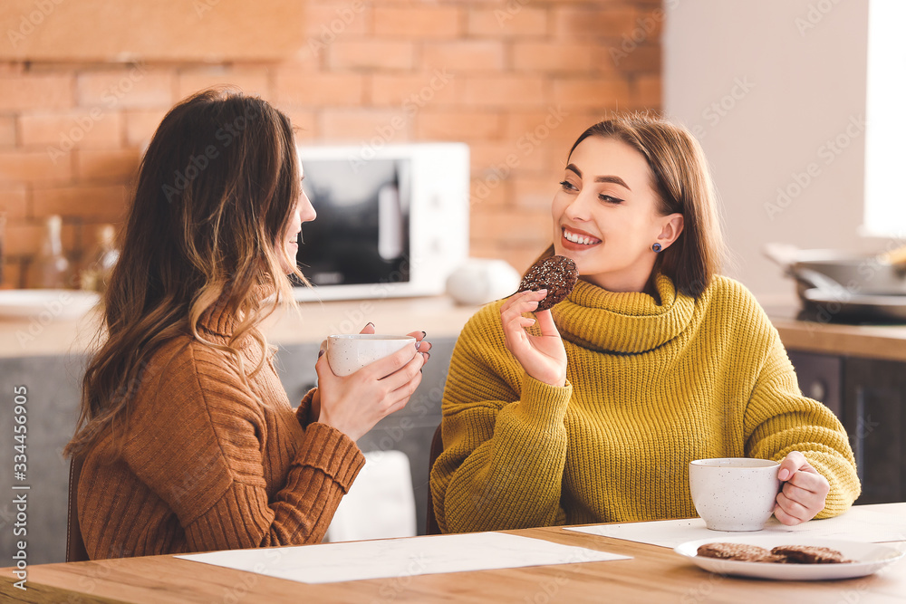 Young women drinking tea in kitchen