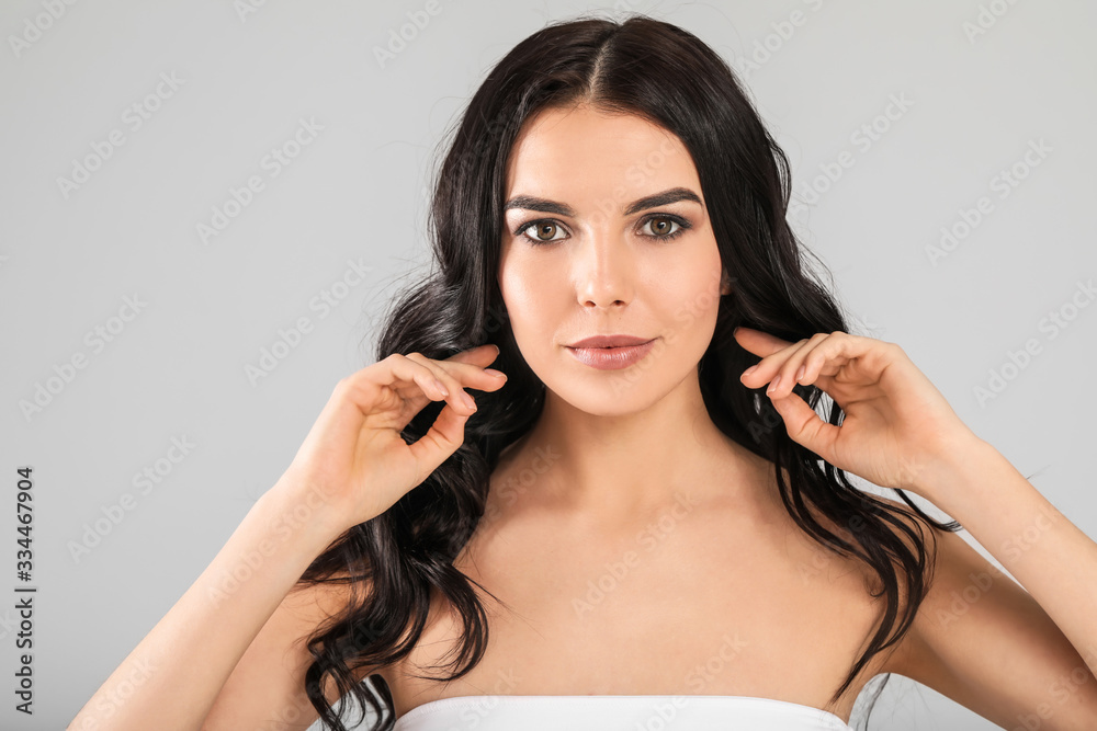 Young woman with beautiful healthy hair on grey background