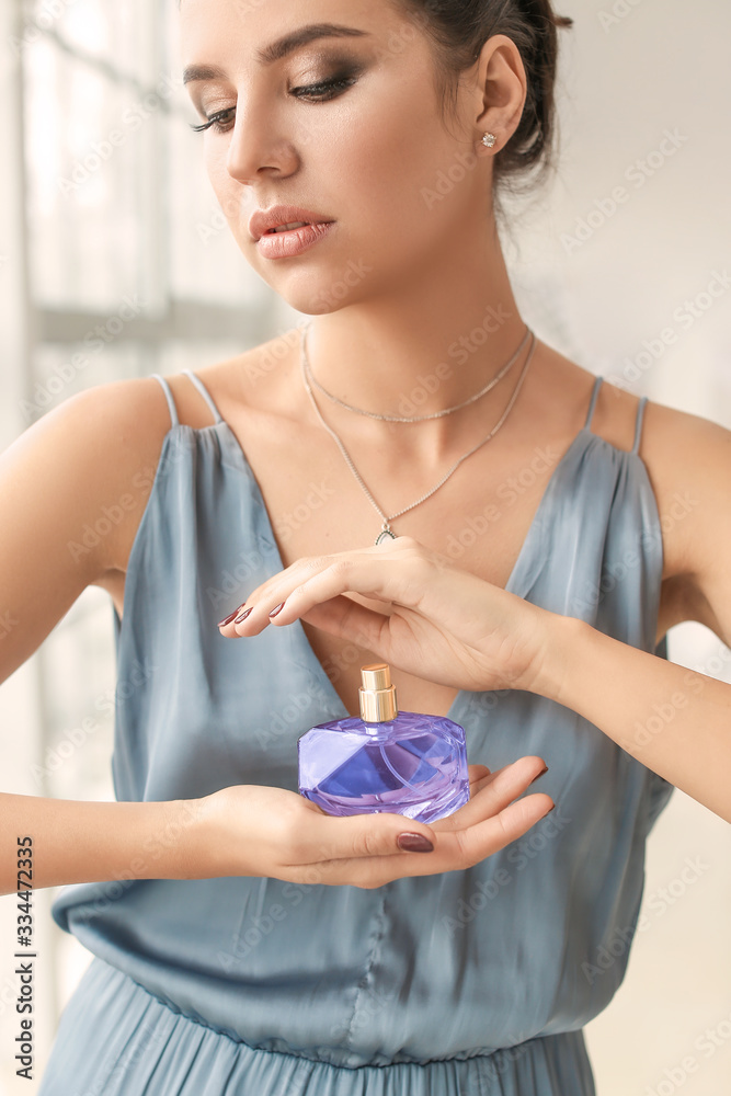 Beautiful young woman with perfume at home