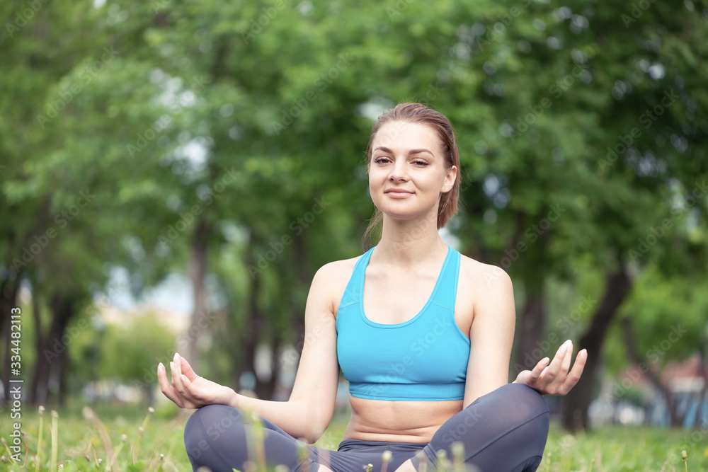 Girl meditates in lotus pose on green grass