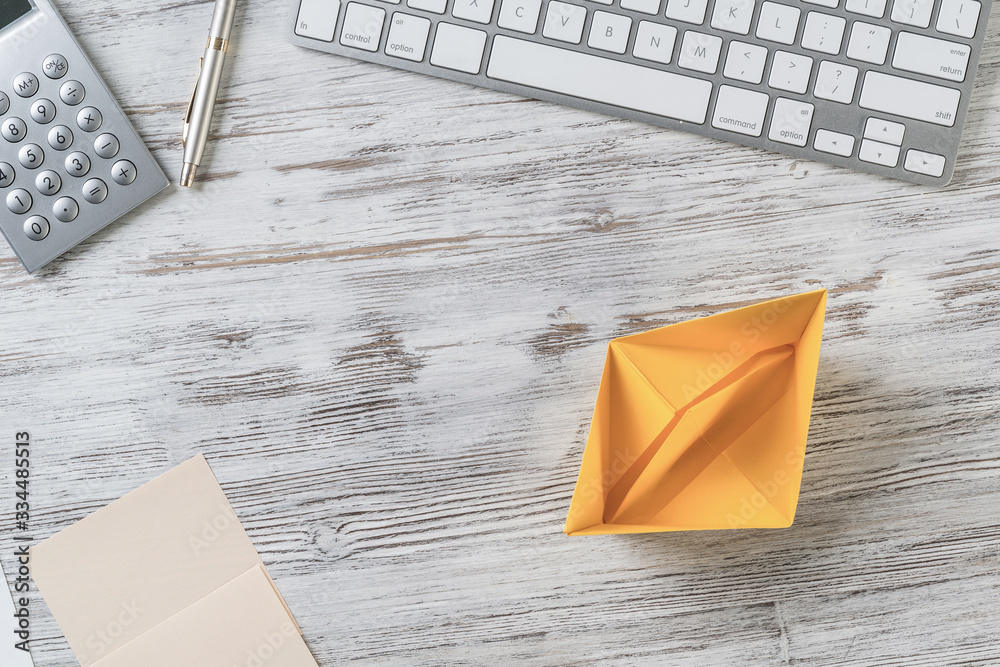 Modern office workspace with yellow paper ship