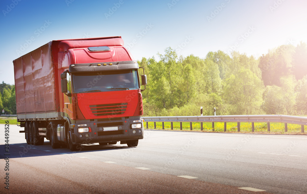 Asphalt road on dandelion field with a small truck