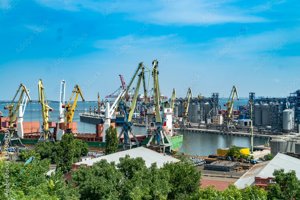 Container cargo freight ship with working crane bridge in shipyard at daytime. Logistic import expor