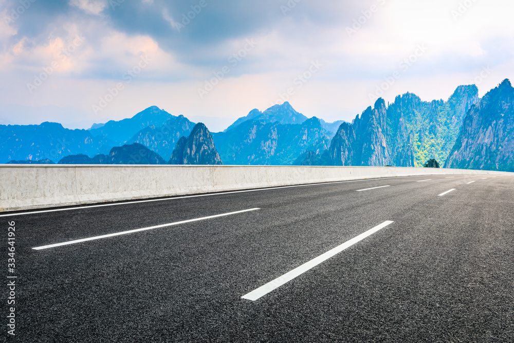 Empty asphalt road and mountain with sky on cloudy day.