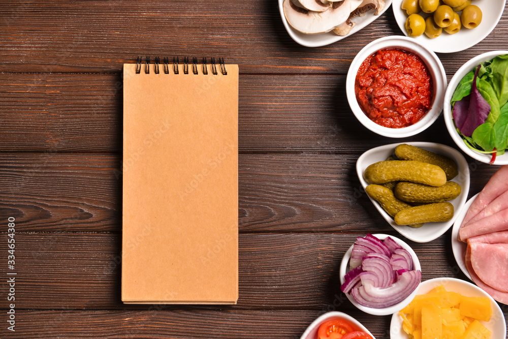 Ingredients for tasty pizza and notebook on wooden background