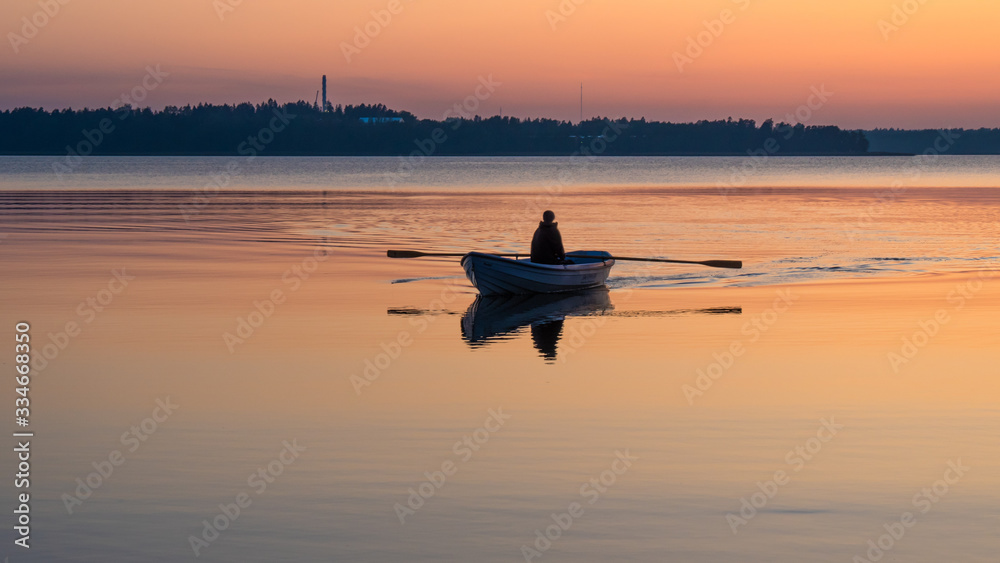 A man rowing a boat on an orange lake at sunset