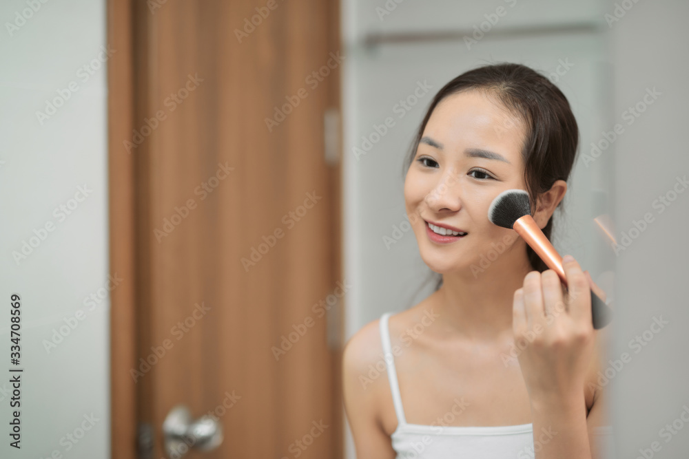 Beautiful woman applying makeup at home