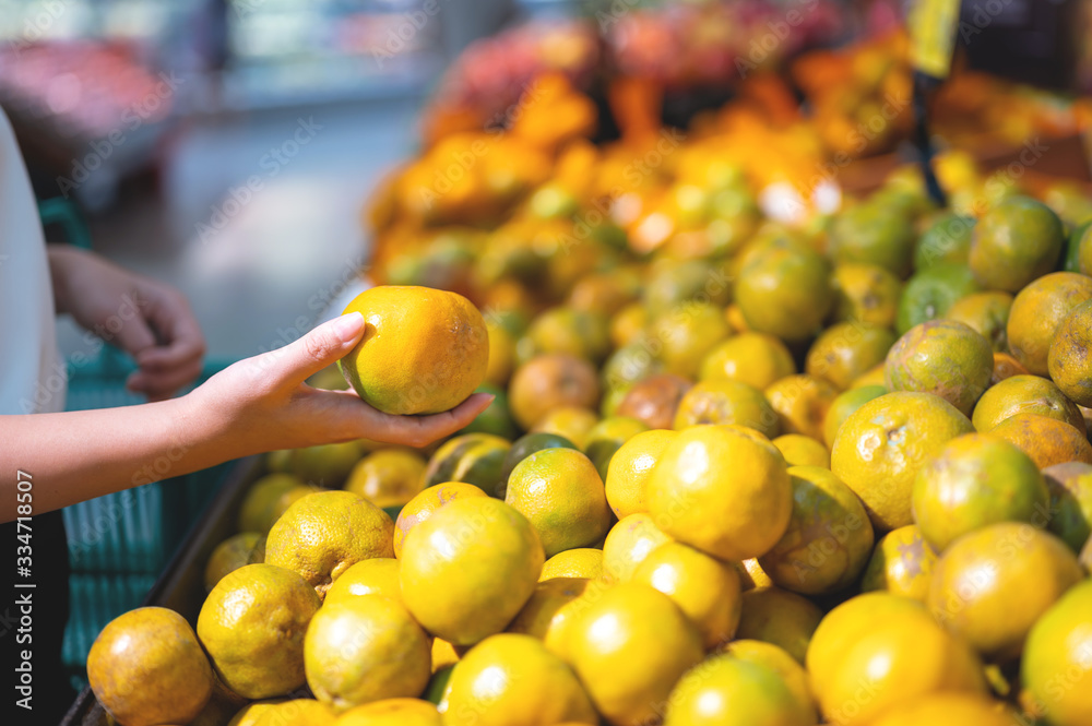 Woman buying fresh orange in groceries