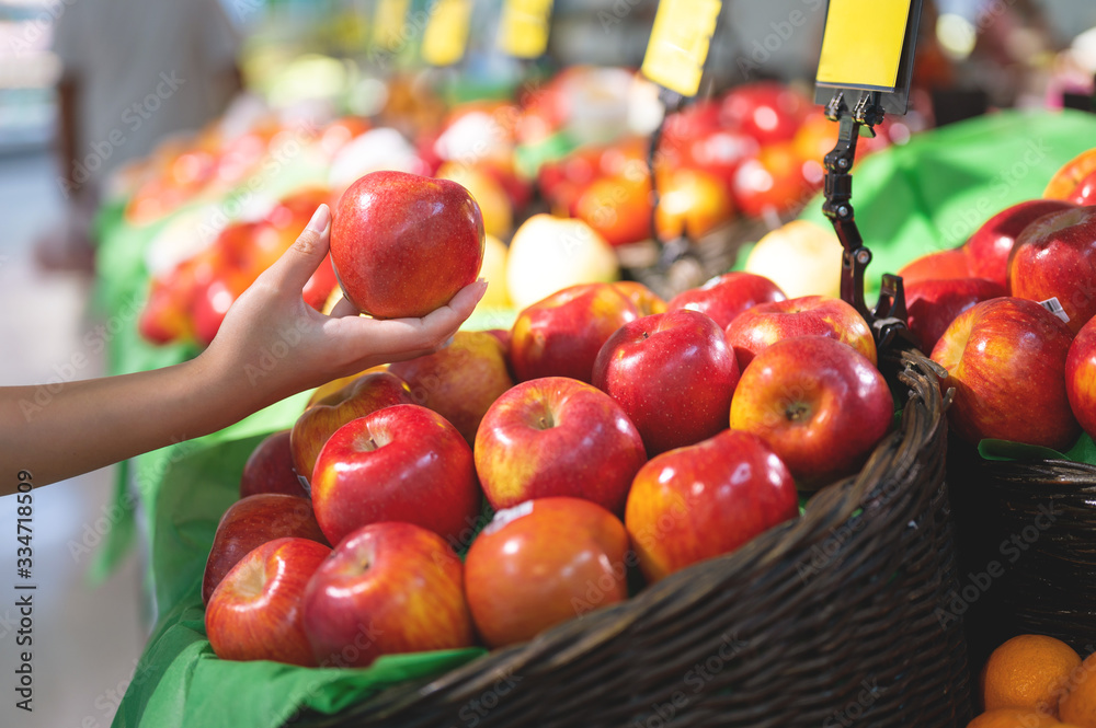 Woman buying fresh apple in groceries