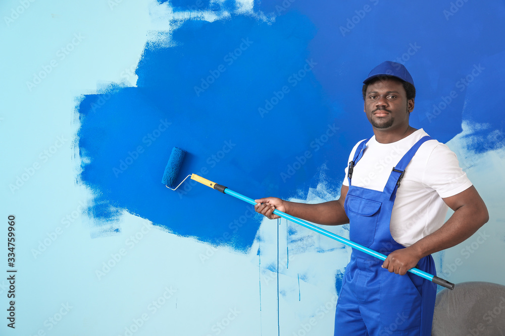 Male worker painting wall in room