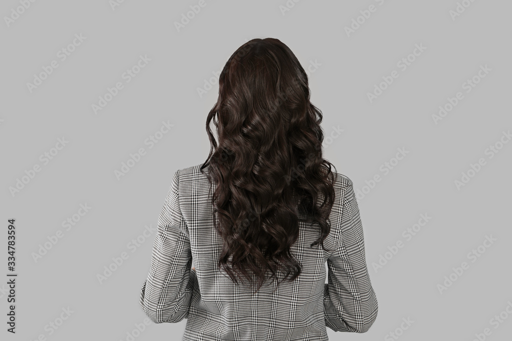 Young woman with beautiful healthy hair on grey background