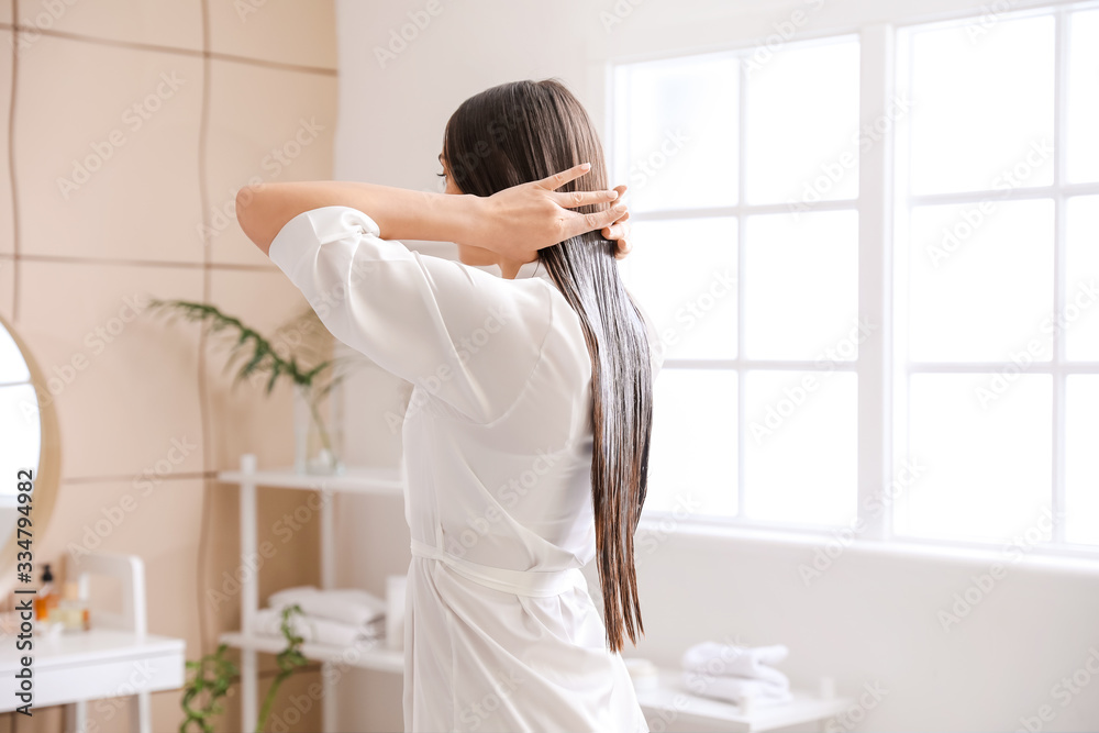 漂亮的年轻女人在家里把椰子油涂在头发上