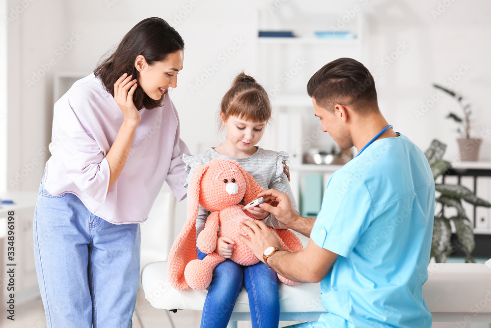 Pediatrician showing little girl how to use thermometer in clinic