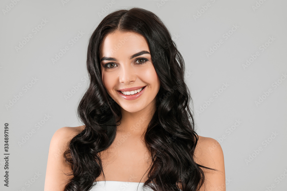 Young woman with beautiful healthy hair on grey background