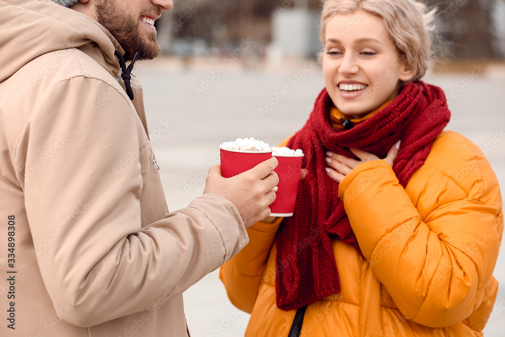 Happy young couple drinking hot cocoa outdoors