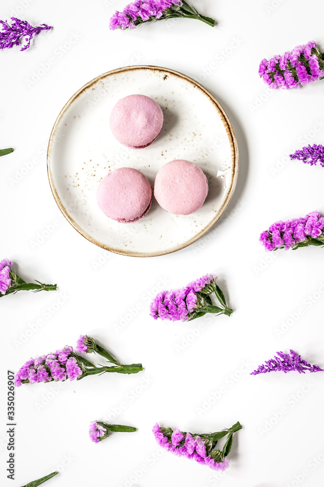 macaroons and flowers for light breakfast on white desk background top view pattern