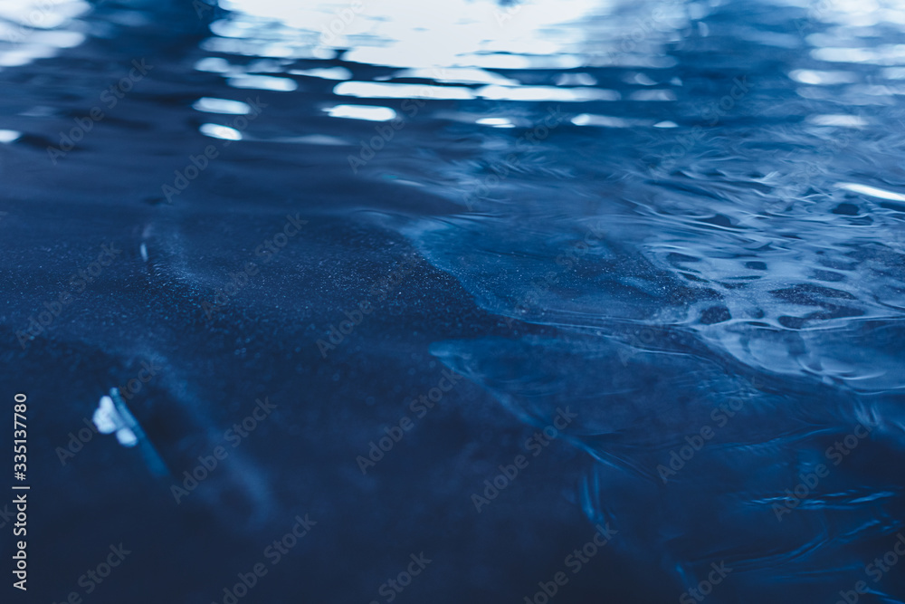 Closeup of calm water surface texture with waves in dark blue color. Trendy fresh abstract nature ba