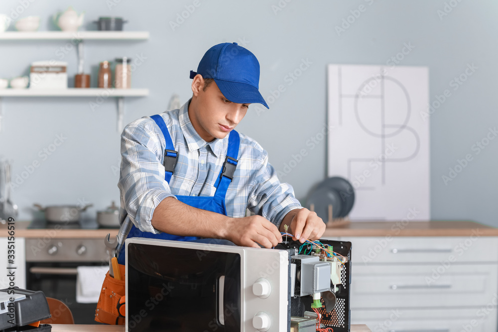 Worker repairing microwave oven in kitchen