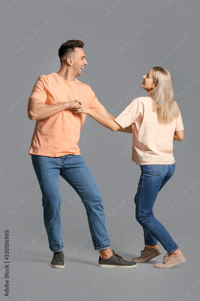 Happy dancing young couple on grey background