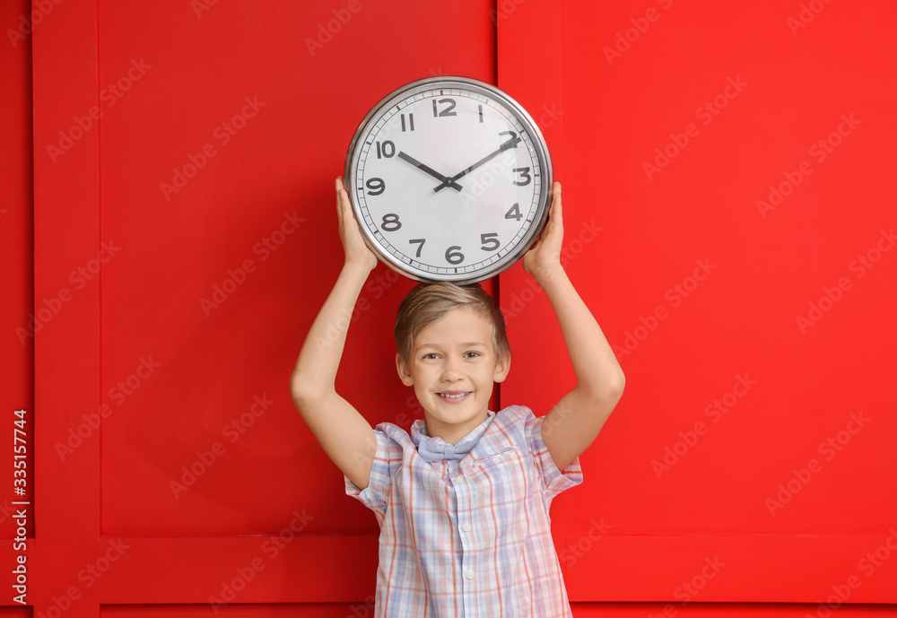 Little boy with clock on color background