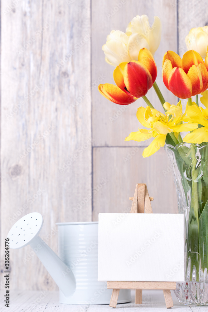 Tulip flower in glass vase with picture frame decor on wooden table background wall at home, close u