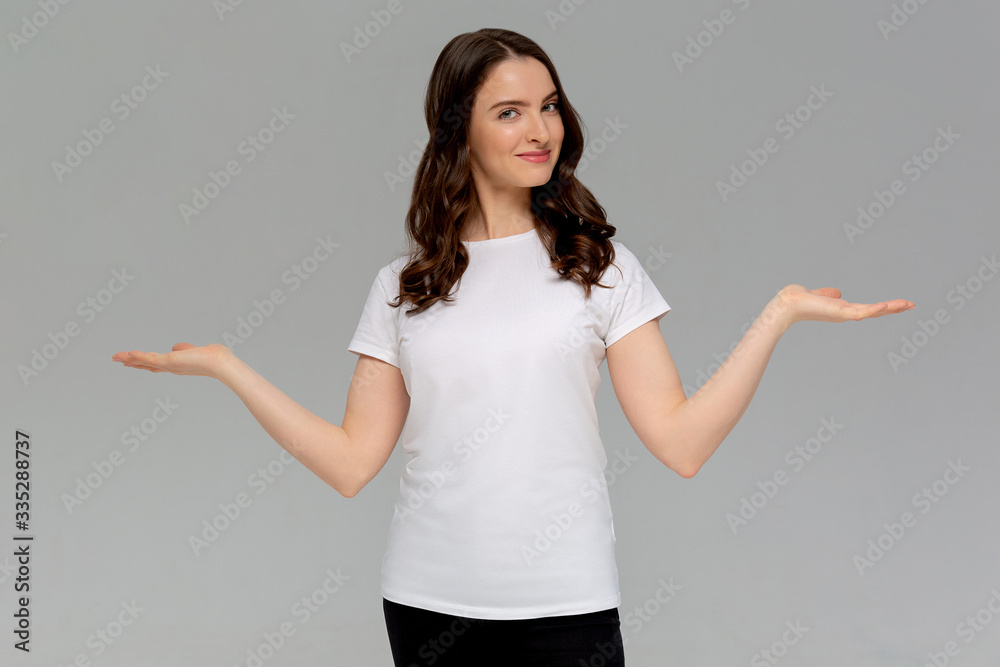 Close up portrait of smiling young woman in white t-shirt throw their hands up looking at camera, is