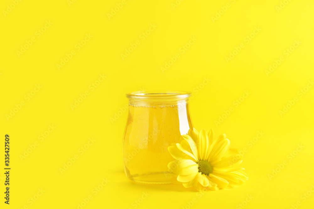 Jar of sweet honey on color background