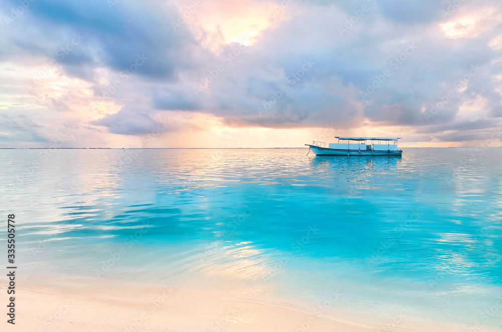 Beautiful natural landscape of coast of a tropical beach with a boat in ocean at sunset with beautif