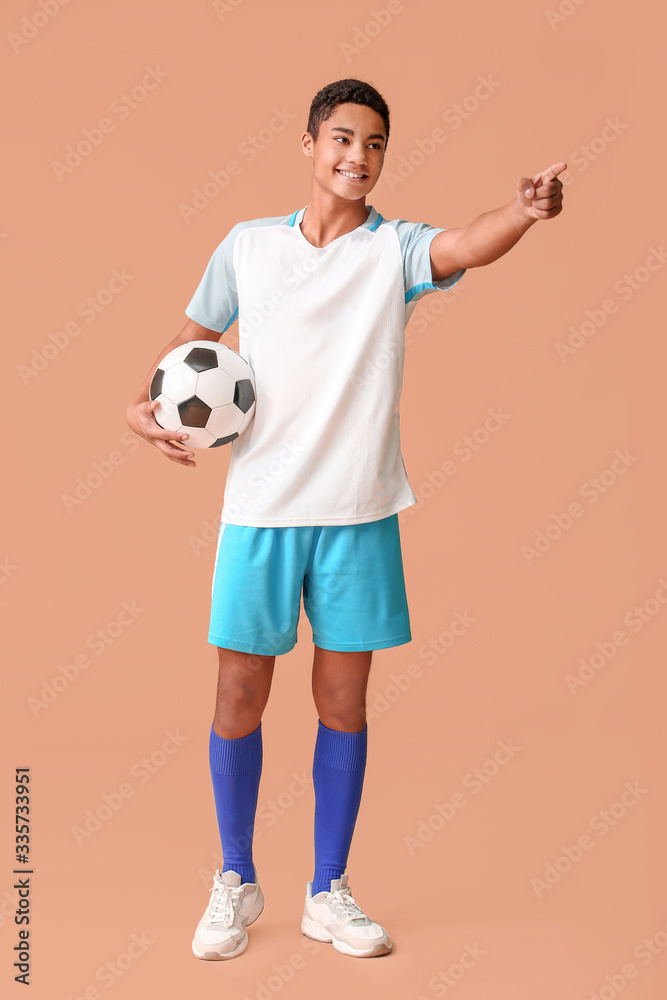 Young African-American football player pointing at something on color background