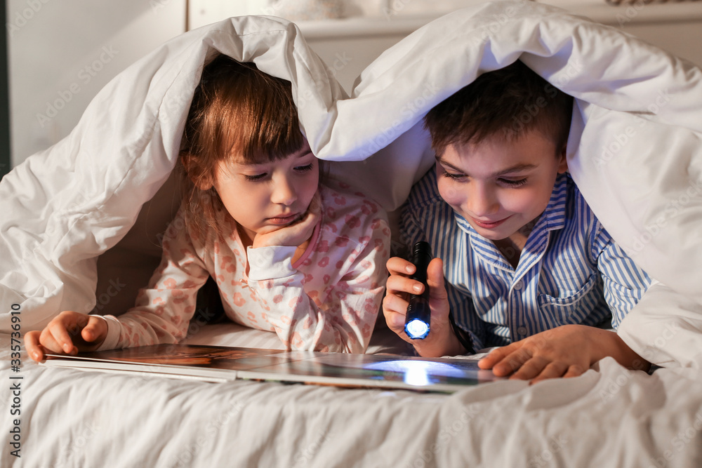 Little children reading bedtime story at home