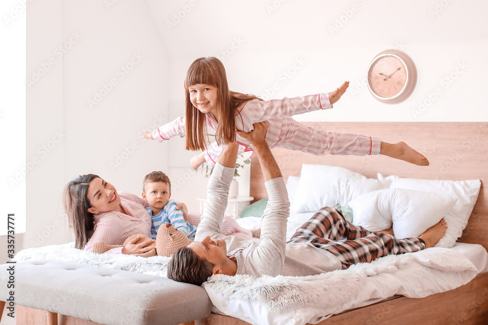 Happy family having fun in bedroom at home