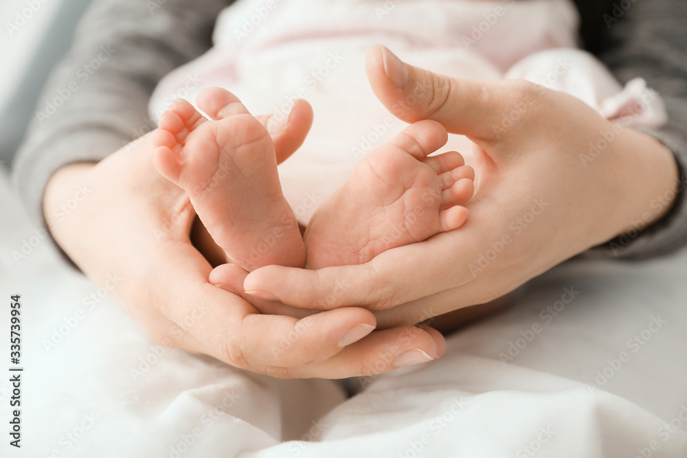 Mothers holding tiny feet of little baby, closeup