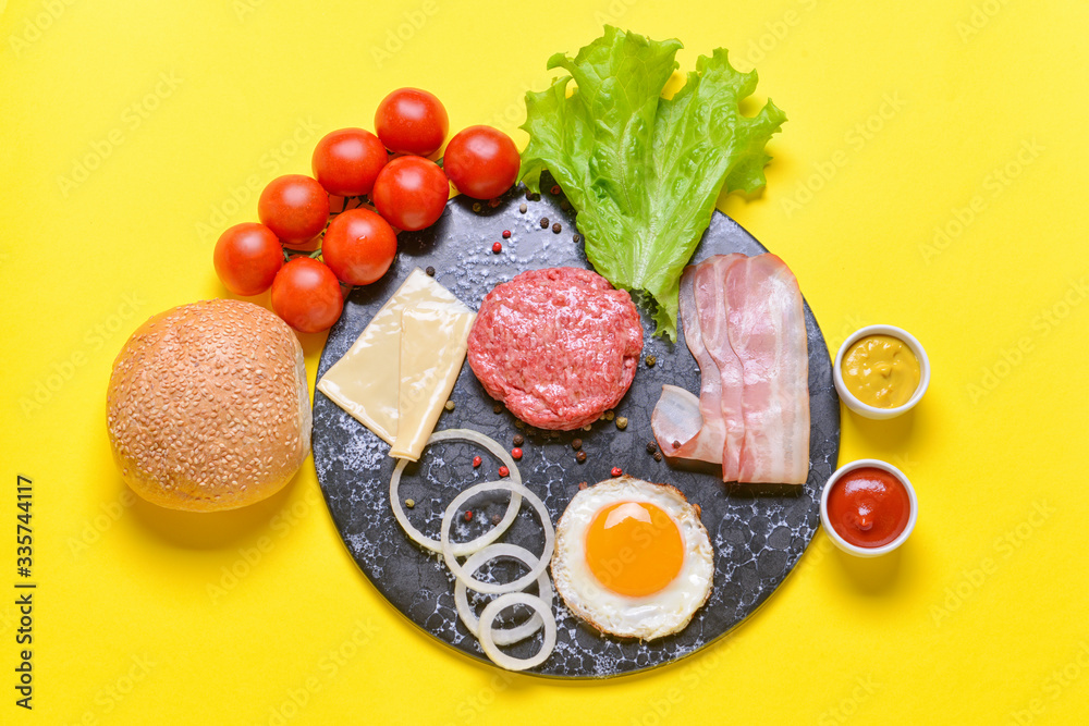 Ingredients for tasty burger on color background