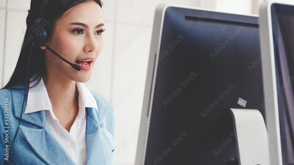 Customer support agent or call center with headset works on desktop computer while supporting the cu