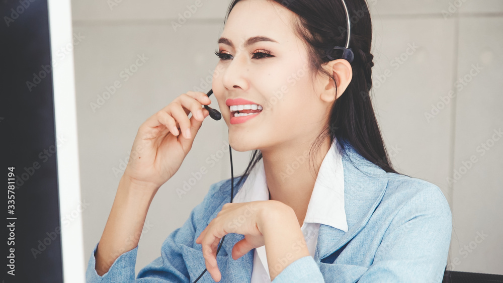 Customer support agent or call center with headset works on desktop computer while supporting the cu