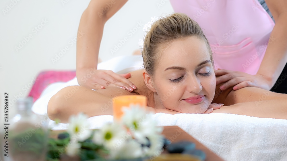 Relaxed woman getting back massage in luxury spa with professional massage therapist. Wellness, heal