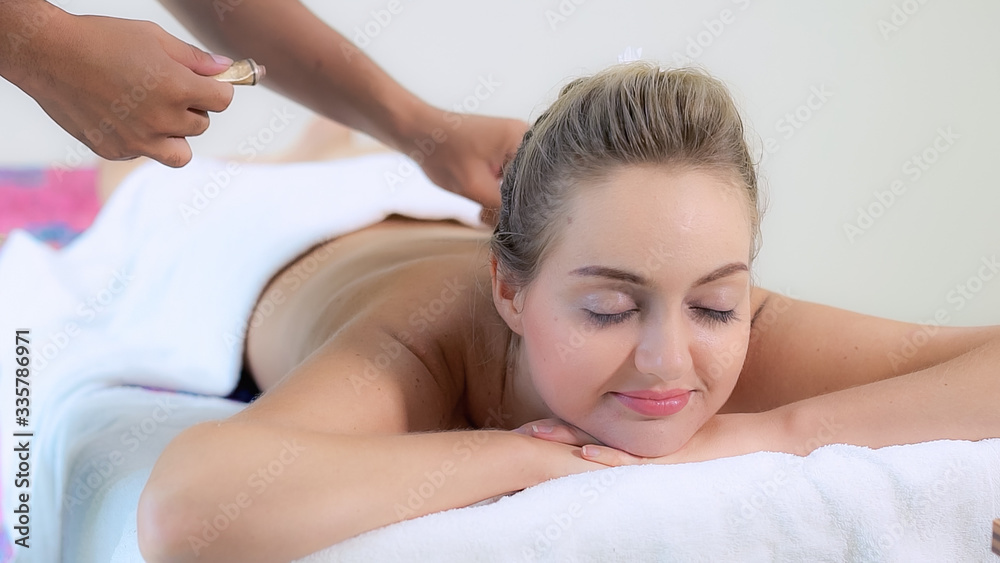 Relaxed woman getting back massage in luxury spa with professional massage therapist. Wellness, heal