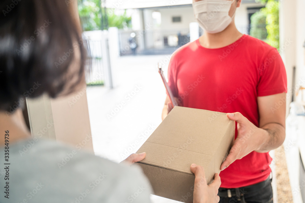 Asian postman or deliveryman carry small box deliver to young woman customer in front of door at hom