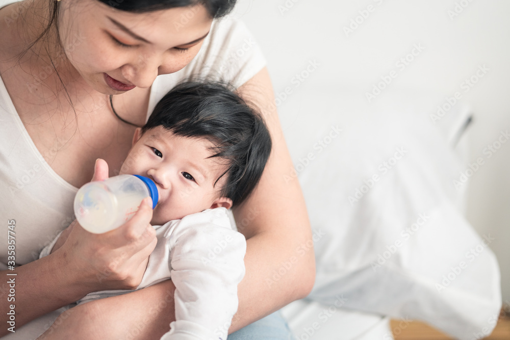 Asian young woman hug, feed milk to cute infant baby boy. Son happy to stay and sleep in mom warm em