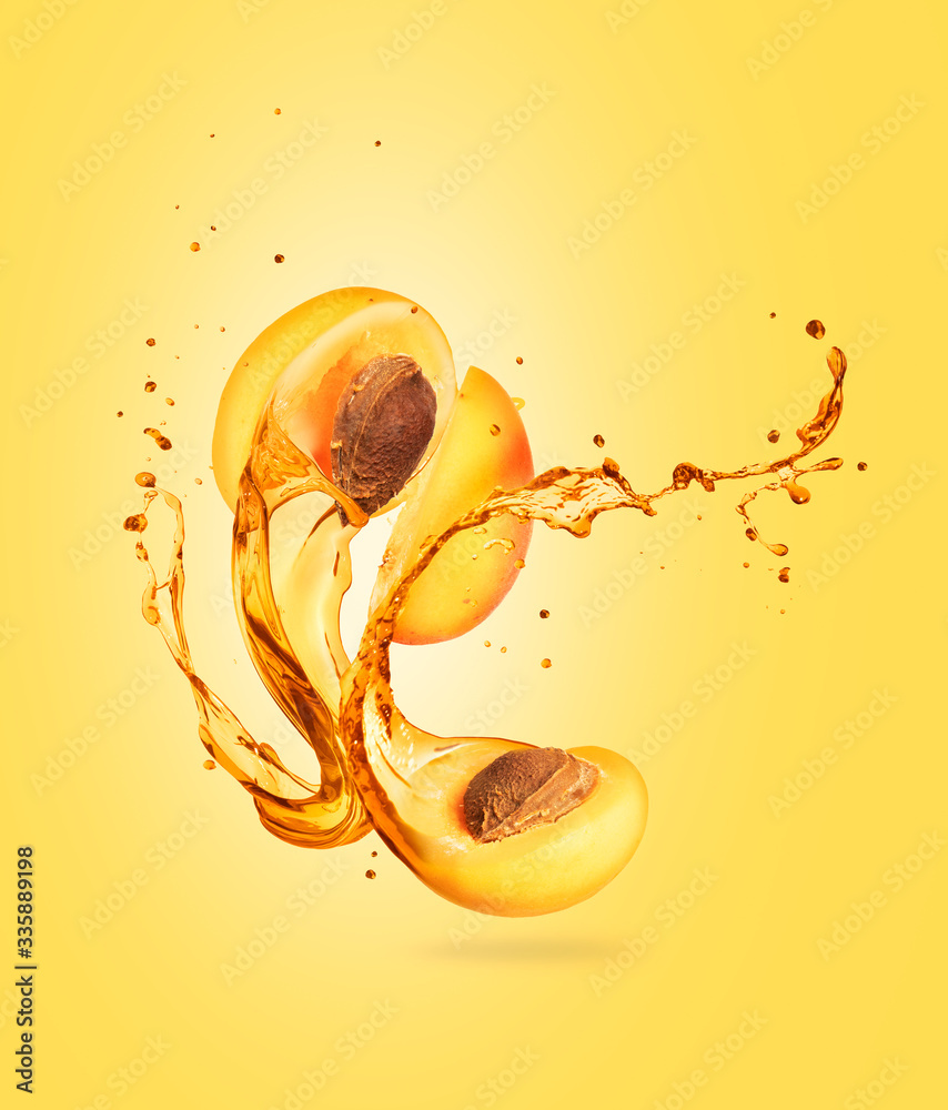 Juice splashes out from the cut apricot on a yellow background