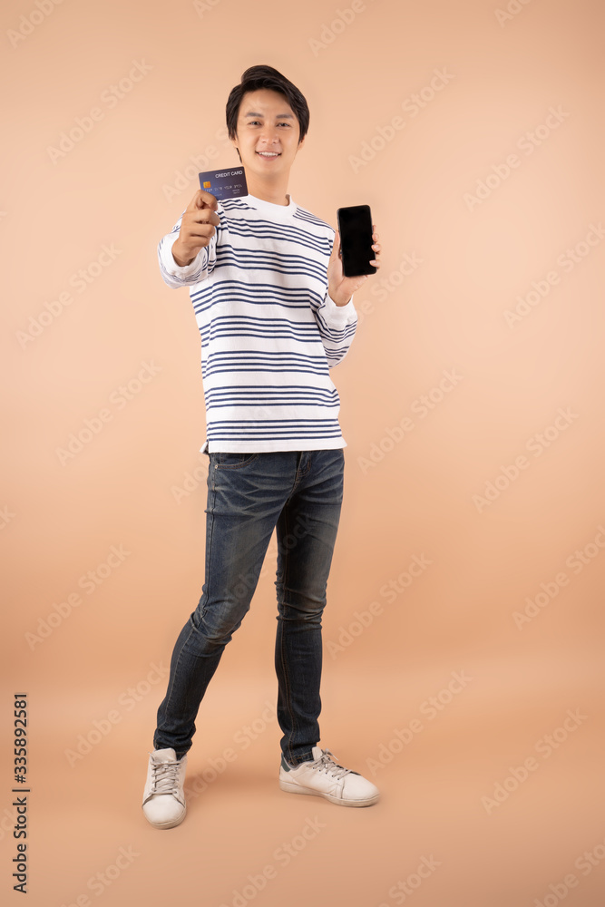 Young Asian man shopping payment online with credit card on smartphone and he showing credit-card  l