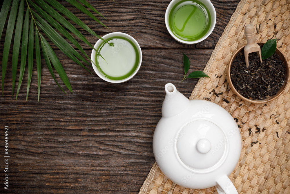 Green Tea cup with teapot, organic green tea leaves and dried herbs on the wooden desk empty space c