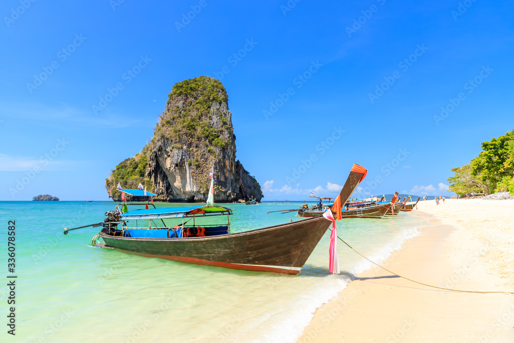 Long tail boat and turquoise crystal clear sea water with limestone cliff and mountain at Phra Nang 