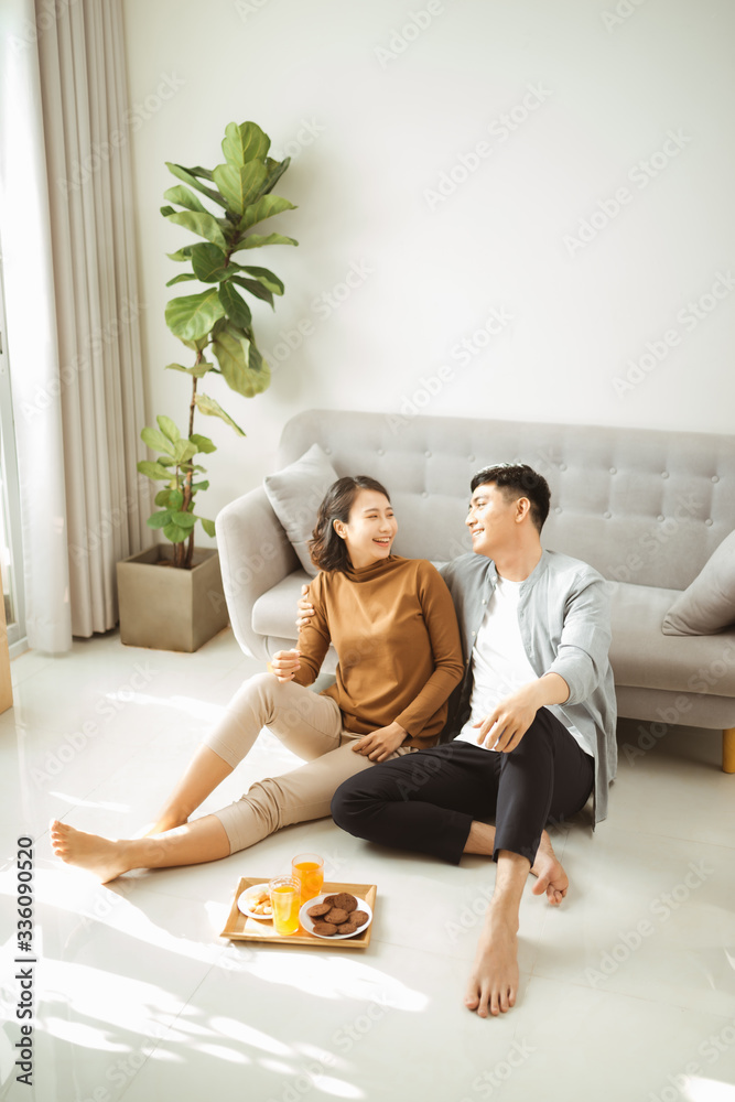 Relaxing at home. Happy young man and woman drinking hot beverage with sweet pastry. They are sittin