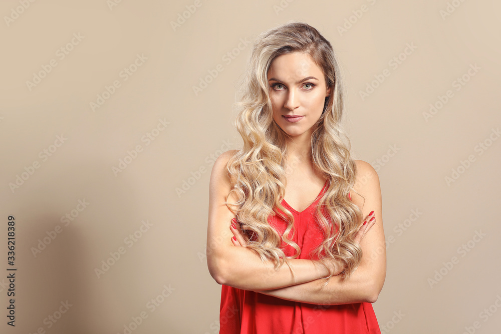 Beautiful young woman with curly hair on light background