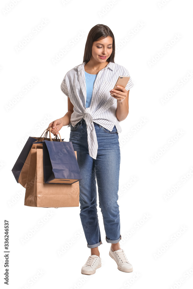 Young woman with mobile phone and shopping bags on white background